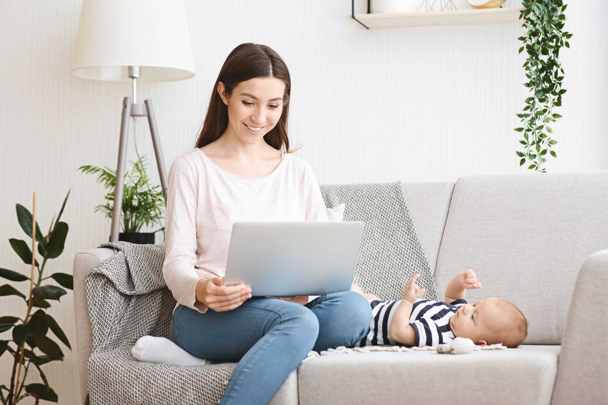 Beautiful young mother reading baby blog on laptop