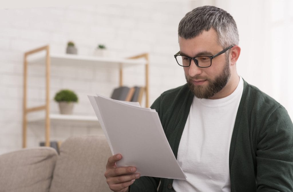 Concentrated man reading printed article, education at home