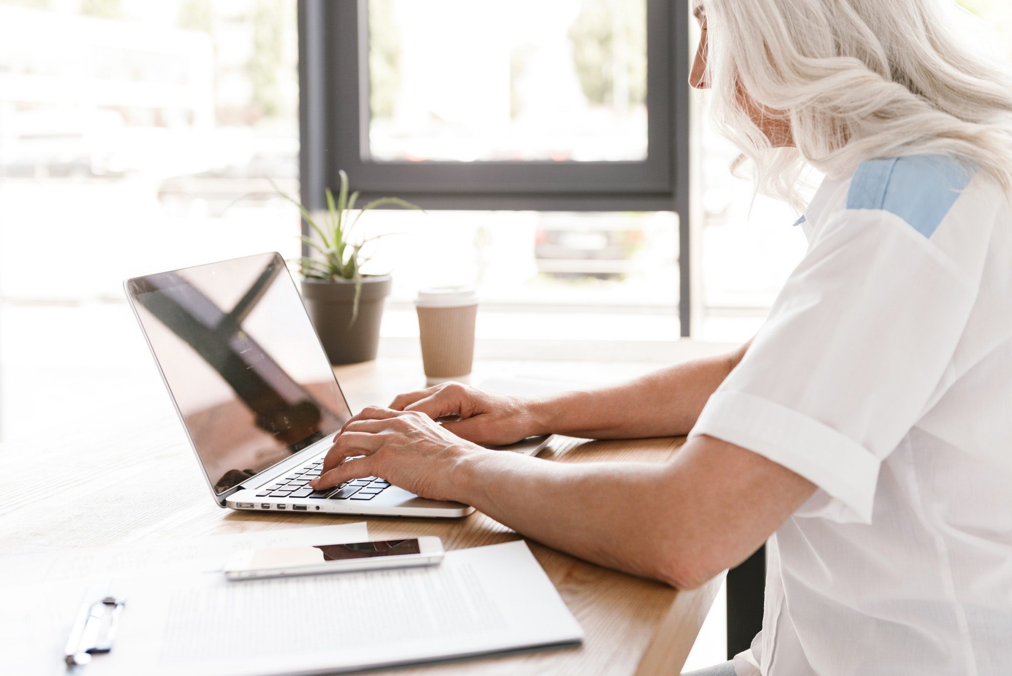 Cropped image of mature woman working with laptop computer.