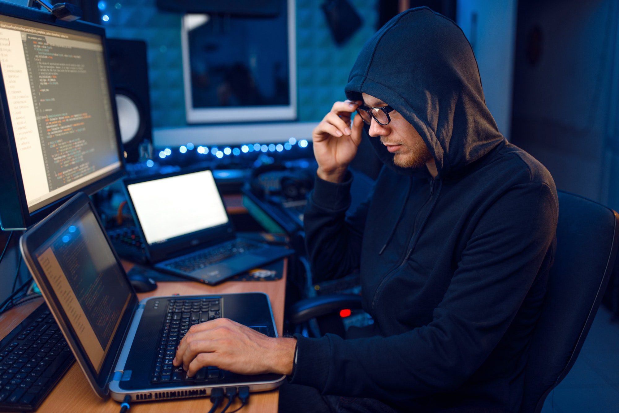 Hacker in hood at his workplace, corporate hacking