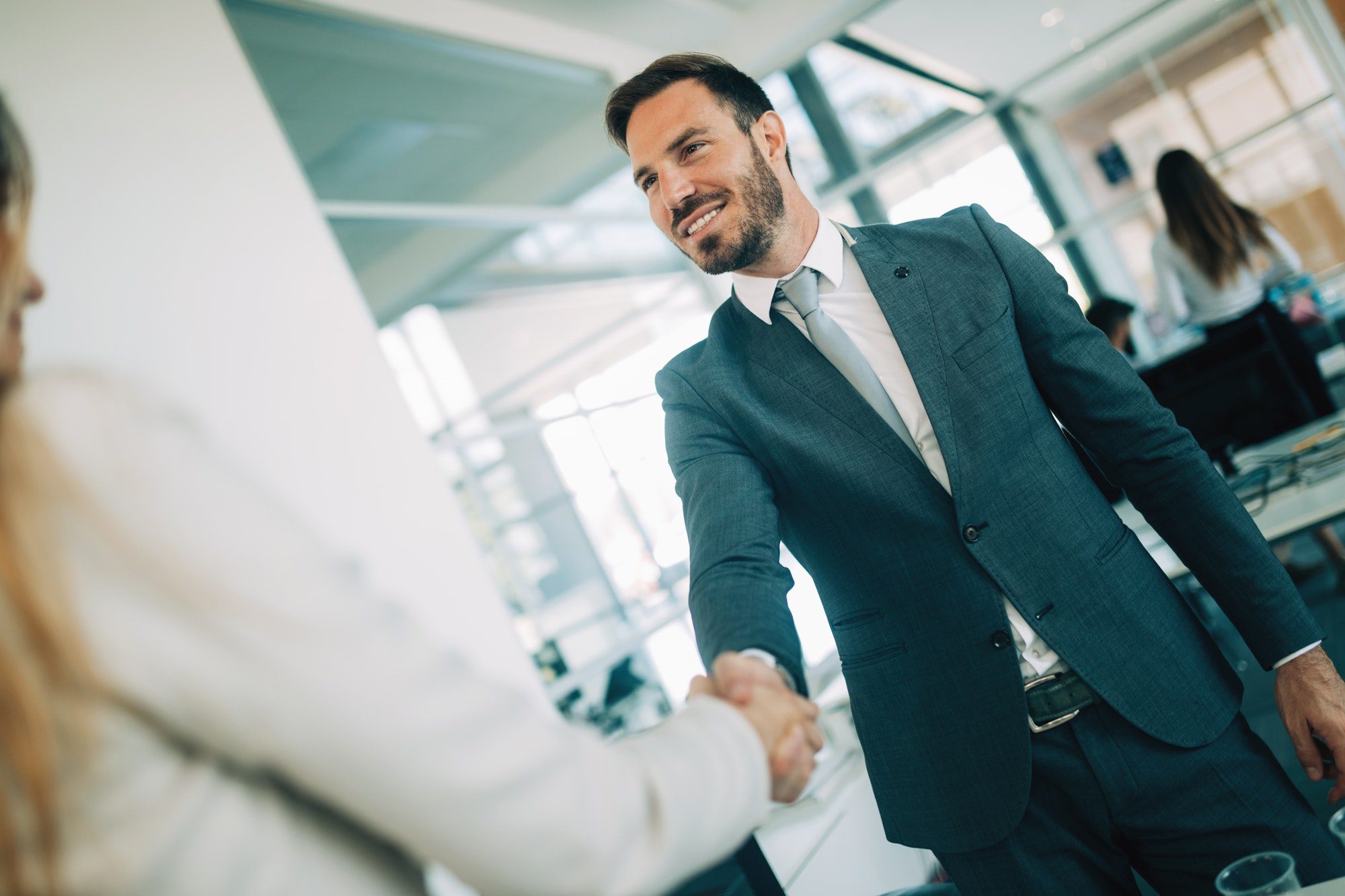 Young businessman and woman shake hands as hello in office portrait